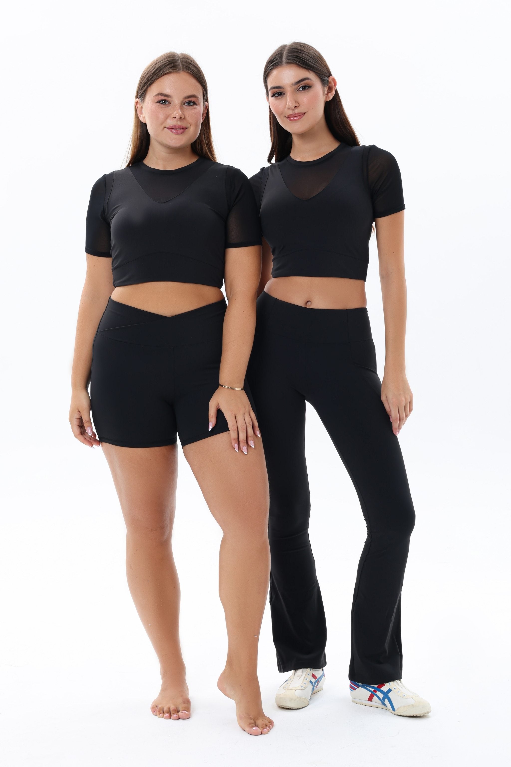 Two women wearing black atheisure outfits stretch flare leggings anf mesh croptop 